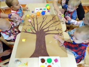 Dzieci siedzą przy stoliku i próbują różnych technik malowania