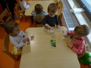 Dzieci siedzą przy stoliku i sieją rzeżuche