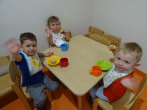 Trójka dzieci siedzi przy stoliku i patrzą w obiektyw
