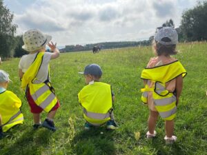 Dzieci stoją na trawce i przygladaja sie