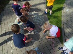 Dzieci malują obrazek namalowany na chodniku