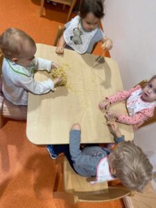Czwórka dzieci przy stoliku bawią się makaronem