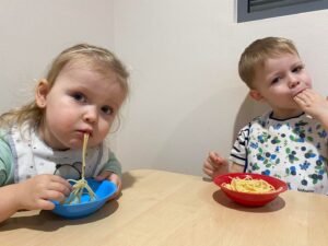 Dwójka dzieci je makaron
