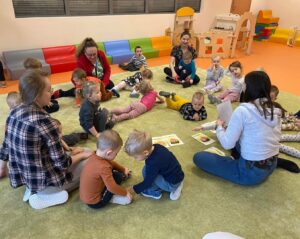 Dzieci siedzą na dywanie i oglądają karyy z emocjami