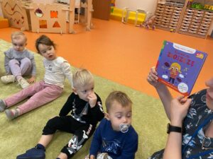 Opiekunka pokazuje dzieciom książke o emocjach