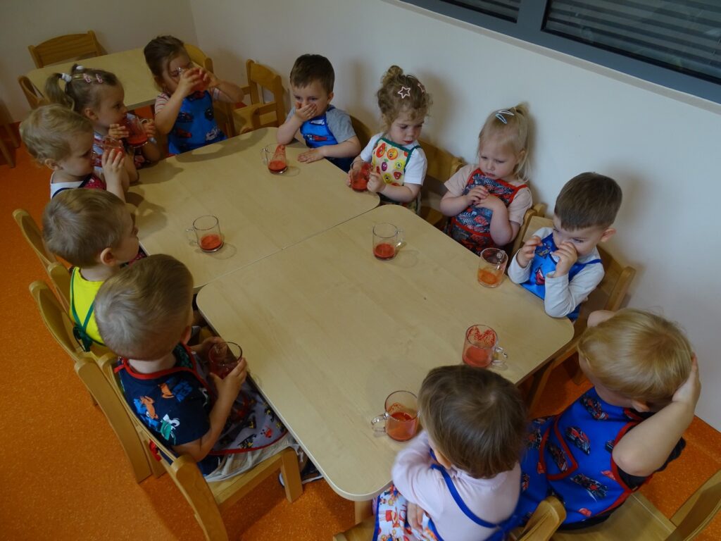 Dzieci siedzą wspólnie przy stolikach