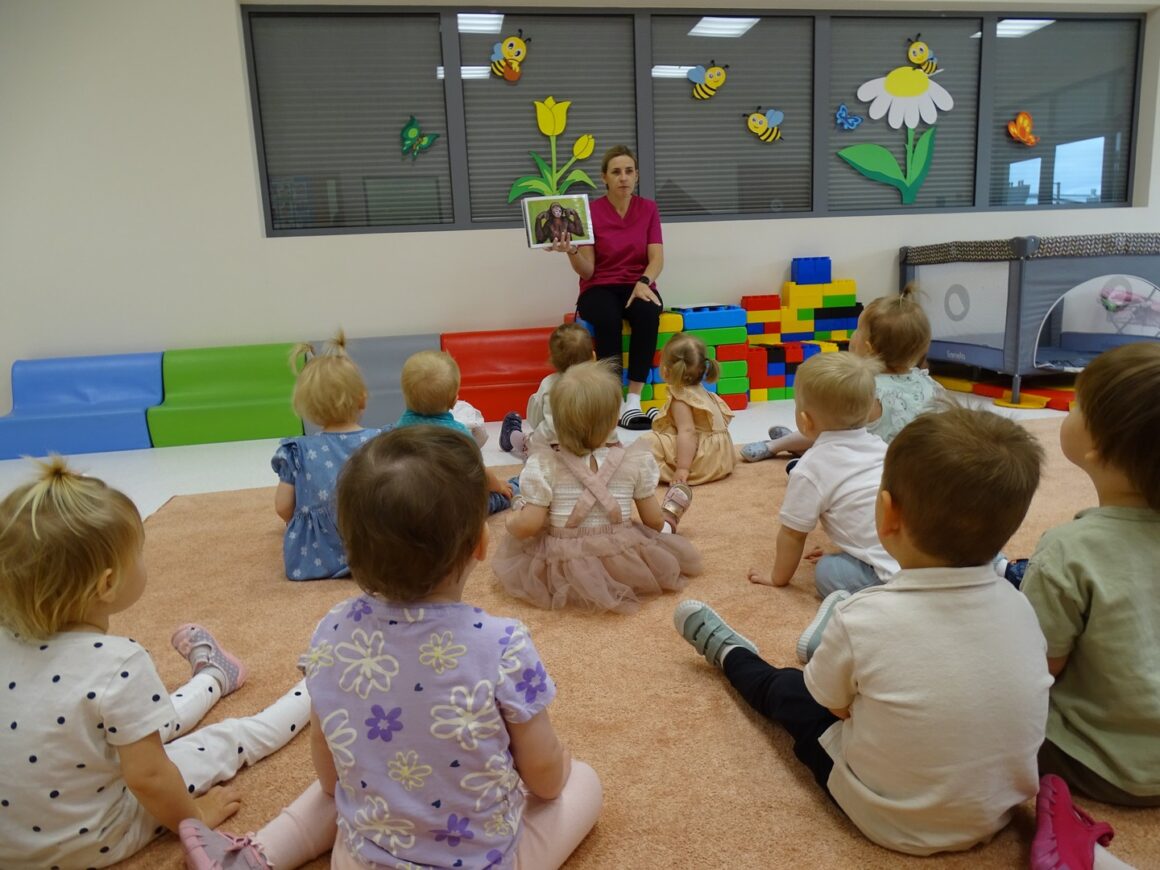 Opiekunka opowiada dzieciom o zwierzątkach mieszkających w zoo