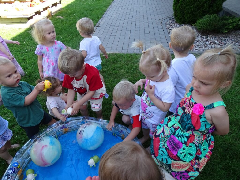 Dzieci wrzucają piłki do wody