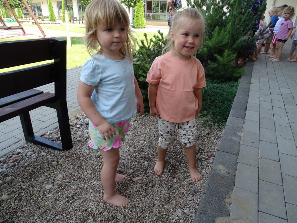Dwie dziewczynki stoją boso na kamyczkach