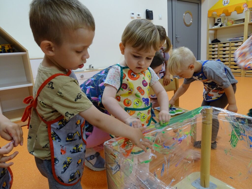 Dzieci rozcierają farbę na folii