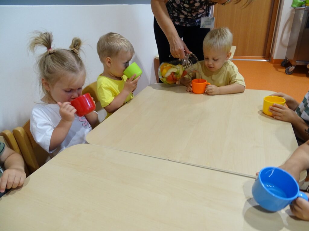 Dzieci piją lemoniadę z kolorowych kubeczków