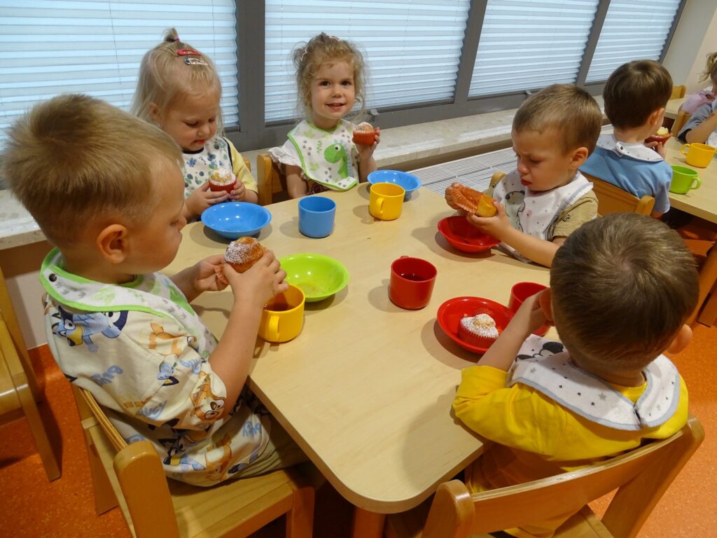 Dzieci jedzą babeczki przy stoliku