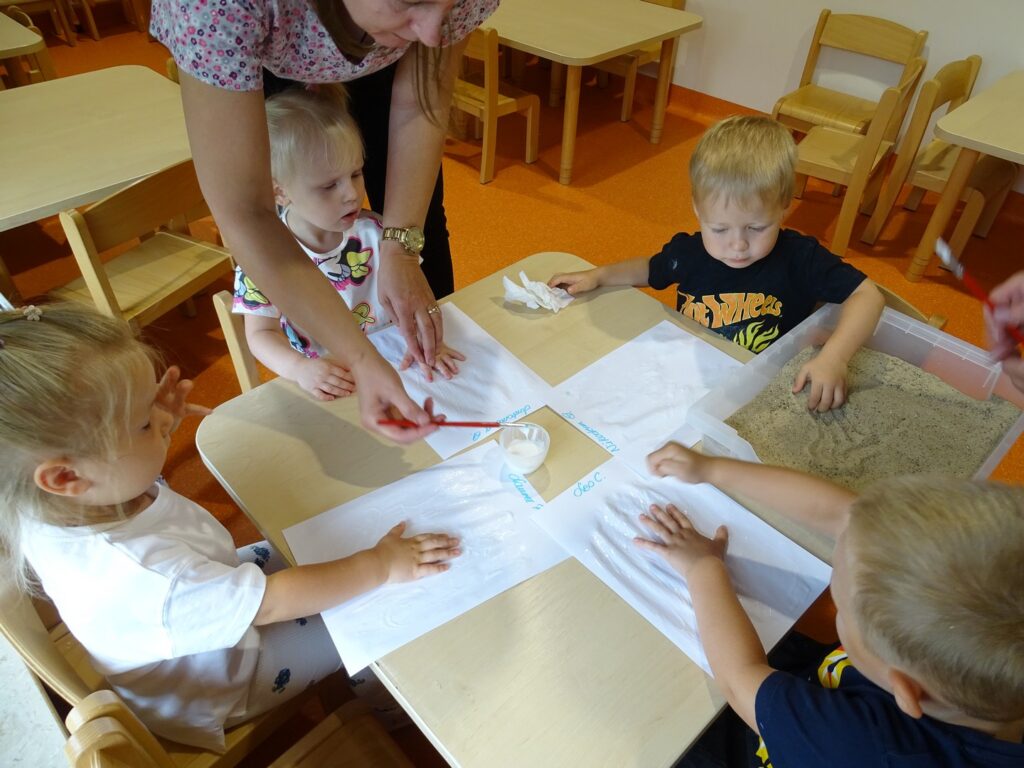 Opiekun pomaga smarować kartkę klejem