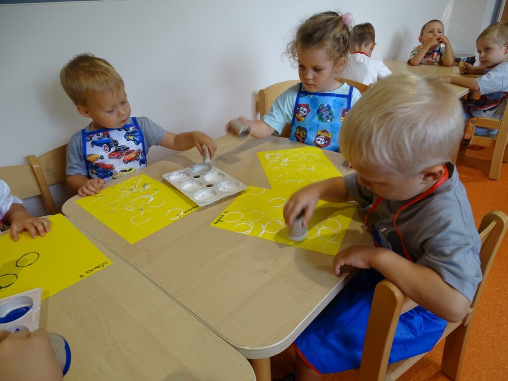 Dzieci odbijają kółeczka białą farbą