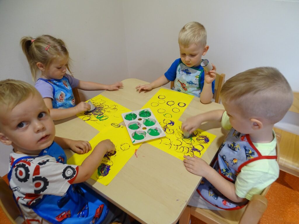 Dzieci przy stoliku wykonują pracę plastyczną