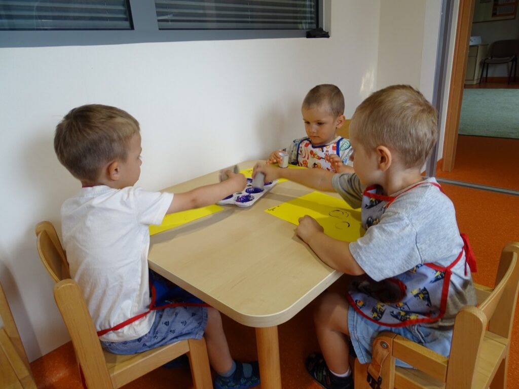 Chłopcy wykonują pracę plastyczną przy stoliku