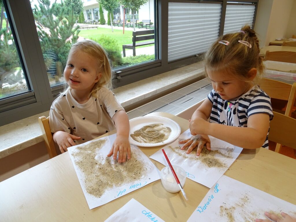 Dziewczynki używają piasku w pracy plastycznej