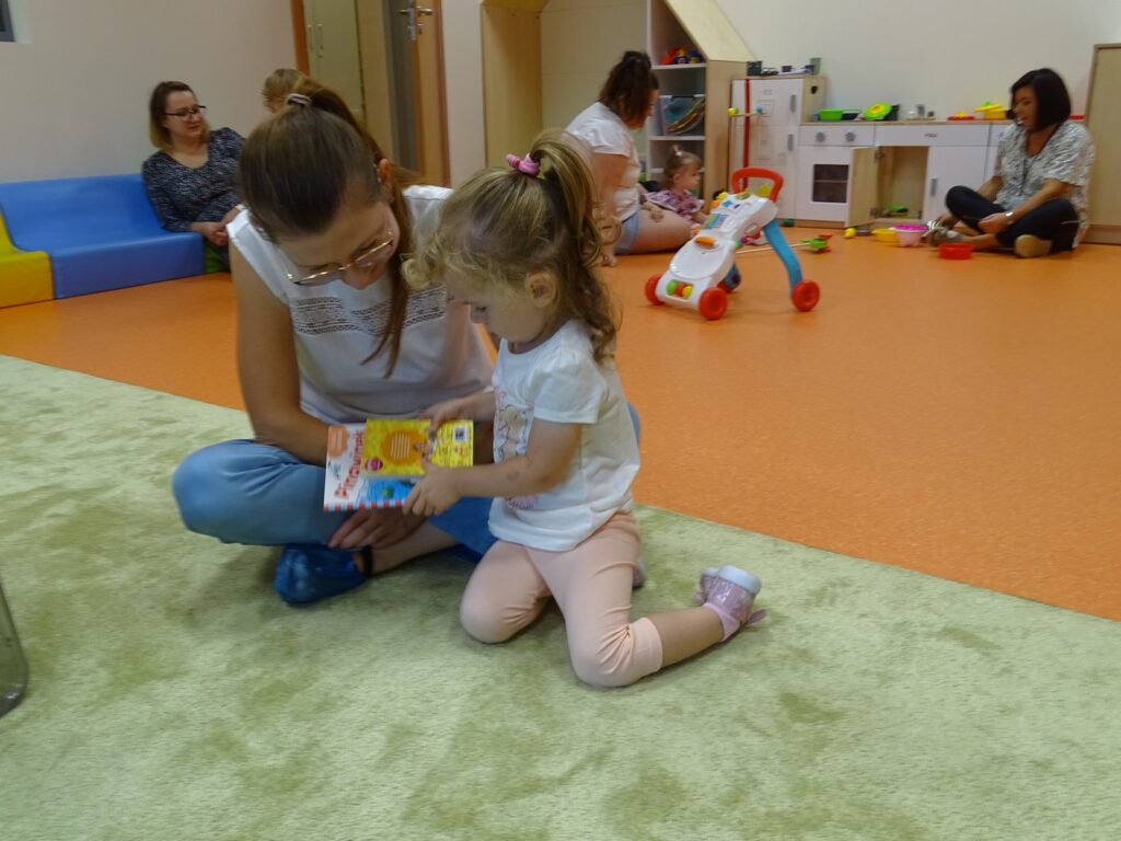Dziewczynka z mamą ogląda książeczkę