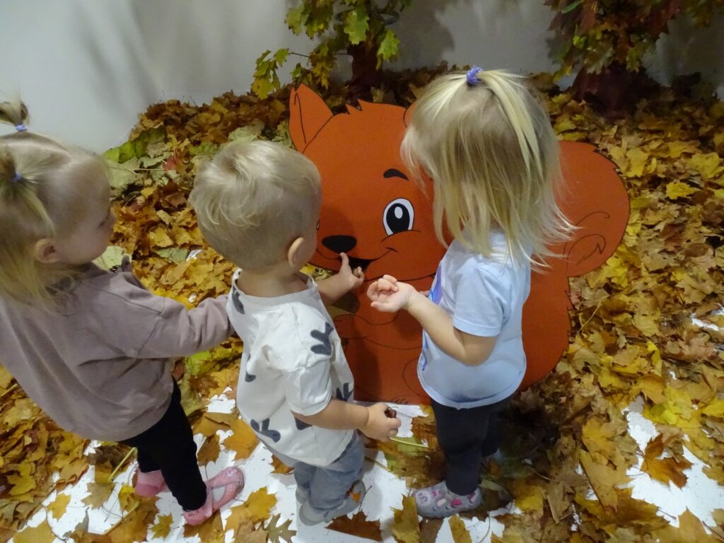 Dzieci karmią wiewiórkę kasztanami