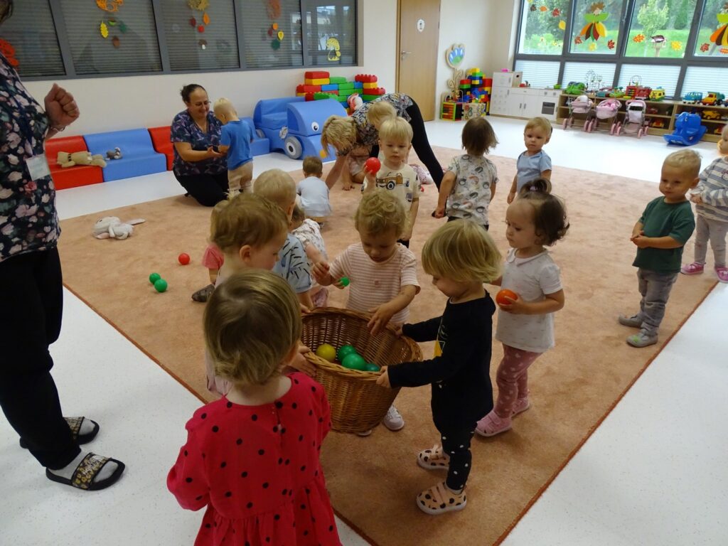 Dzieci wkładają piłeczki do koszyka