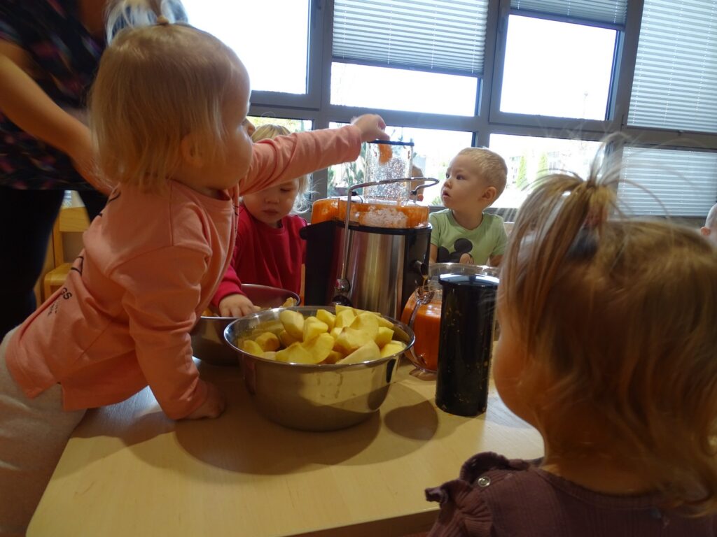 Dziewczynka wrzuca owoce do sokowirówki