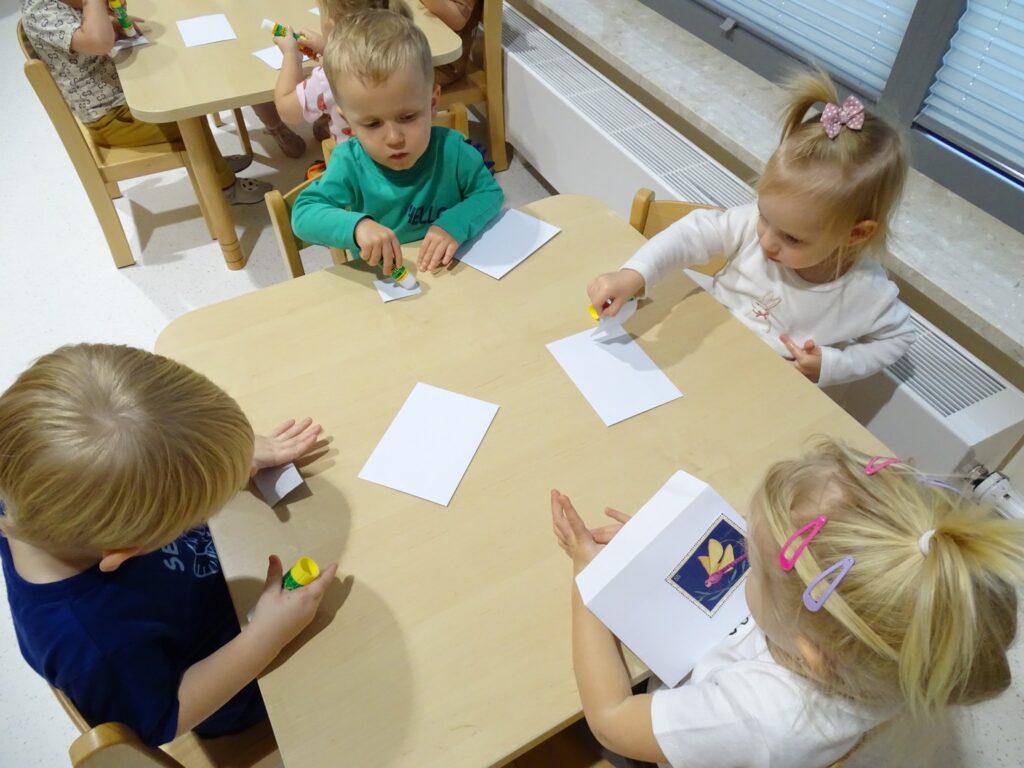 Chłopczyk smaruje klejem znaczek