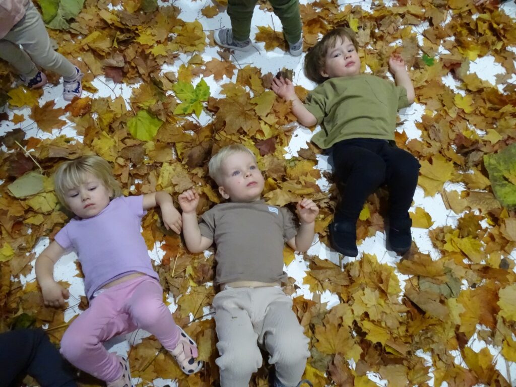Dzieci leżą w jesiennych listkach