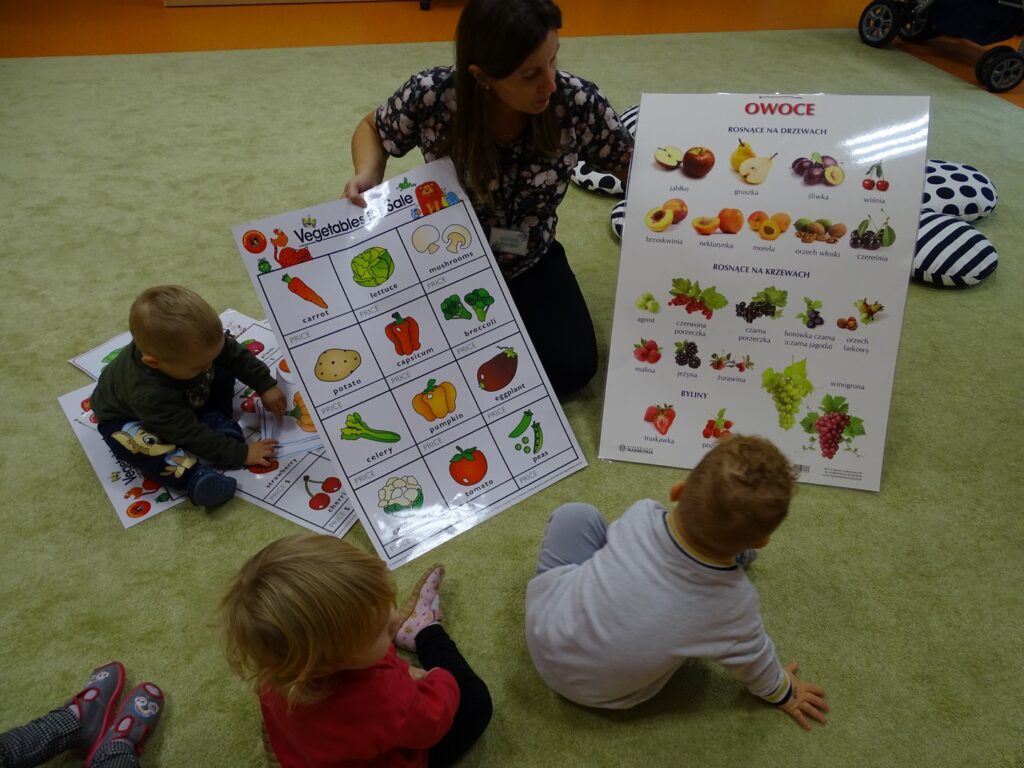 Opiekun trzyma karty z obrazkami owoców i warzyw