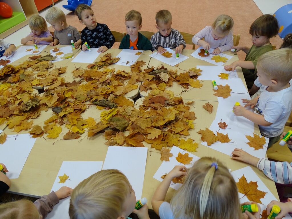 Dzieci naklejają listki na kartkę