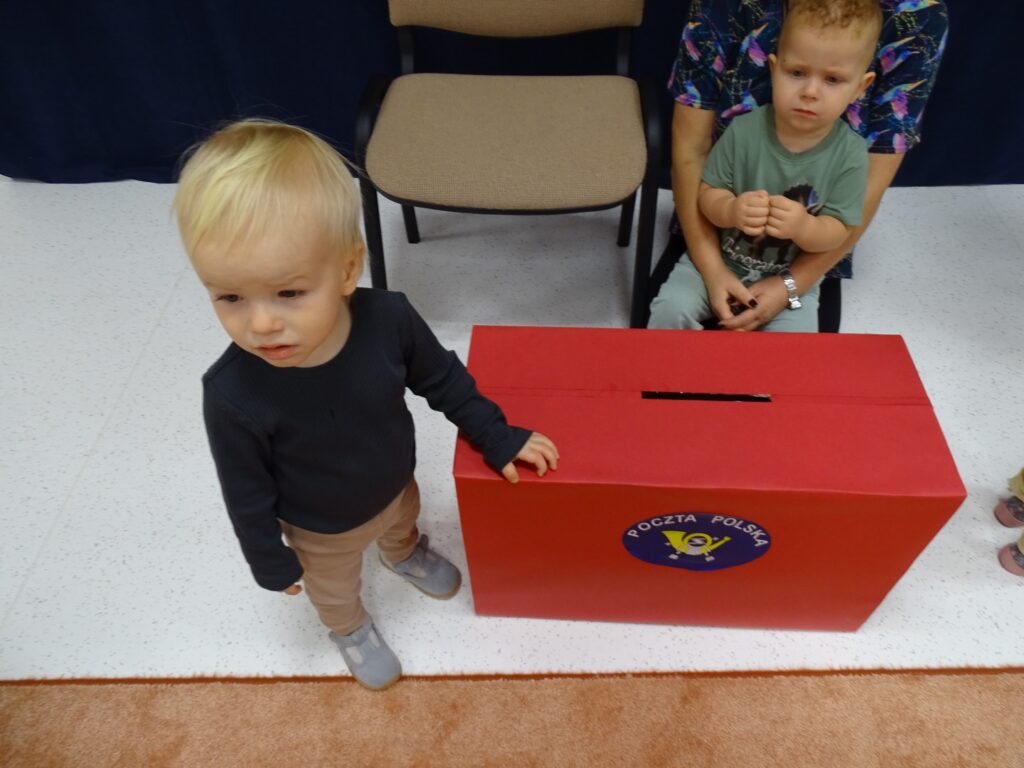 Chłopczyk stoi obok skrzynki pocztowej