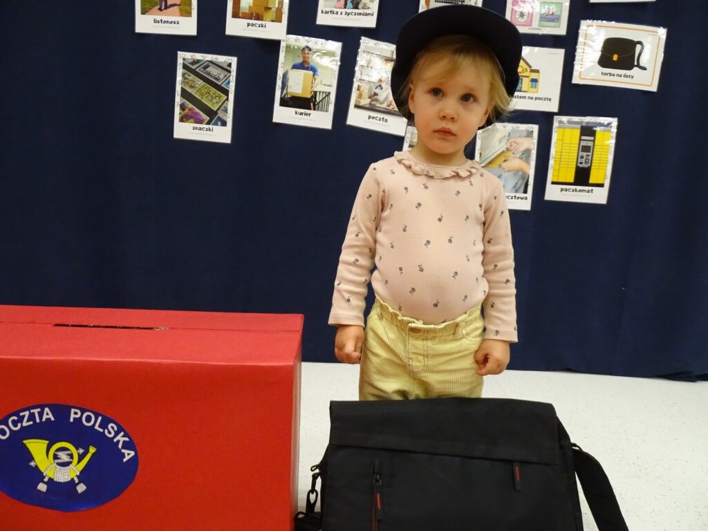 Dziewczynka pozuje do zdjęcia w czapce listonosza