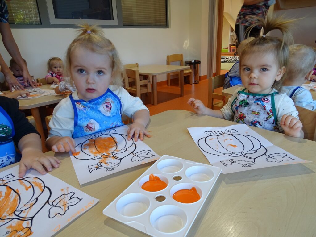 Dziewczynki kolorują dynię na pomarańczowo