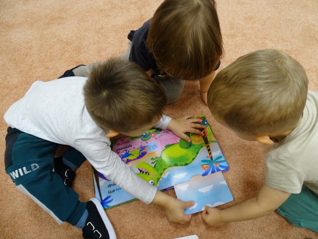 Chłopcy oglądają książkę o dinozaurach