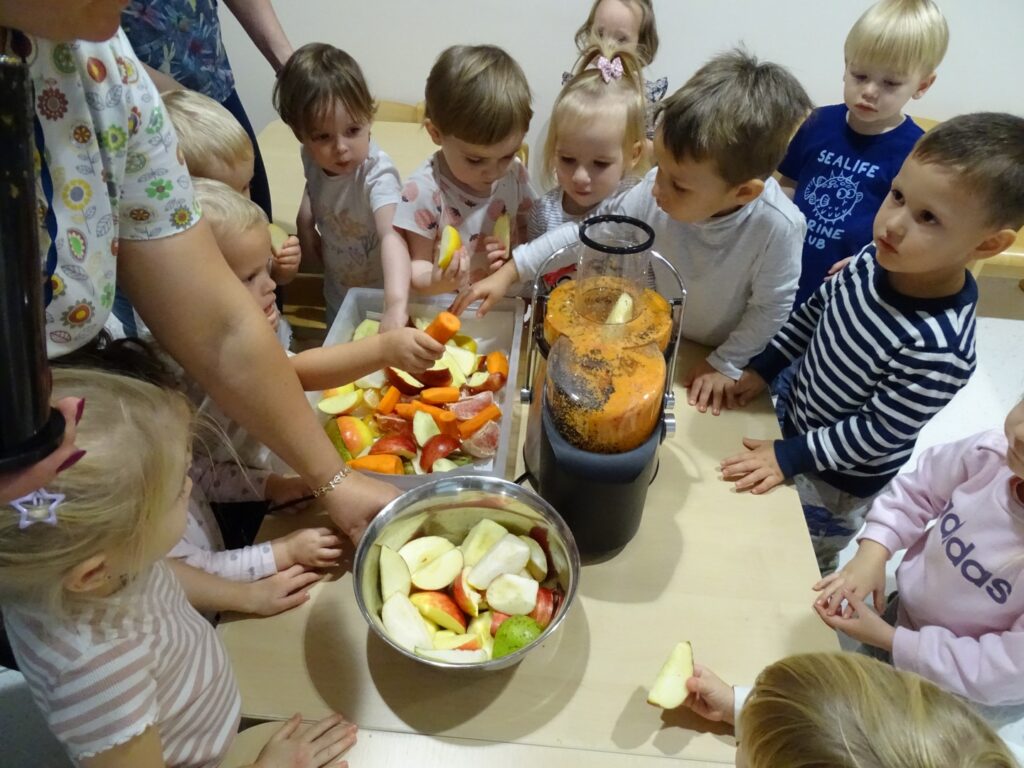 Dzieci wrzucają owoce i warzywa do sokowirówki