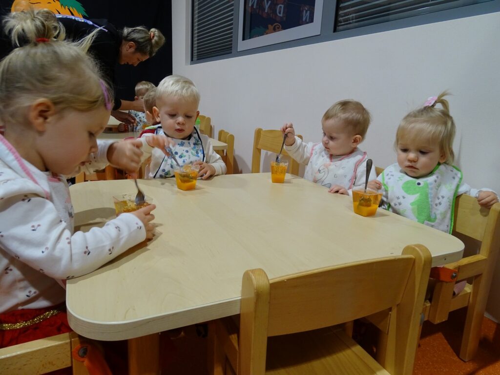 Dzieci jedzą pomarańczowy deserek