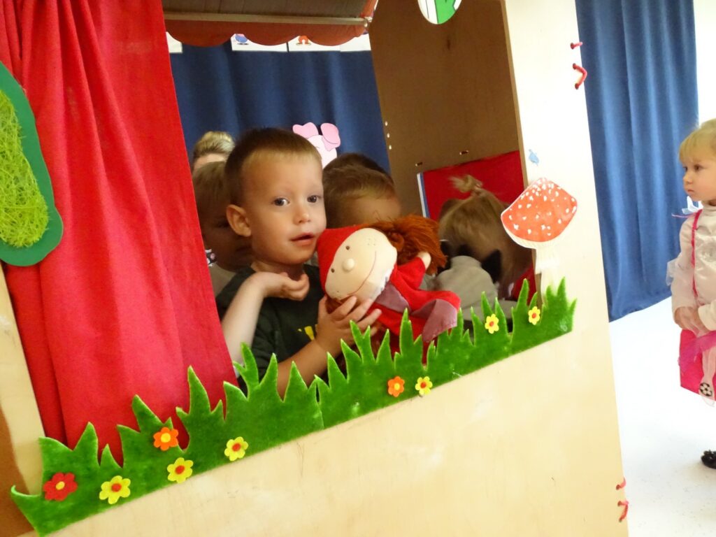 Chłopczyk trzyma pacynkę Czerwonego Kapturka