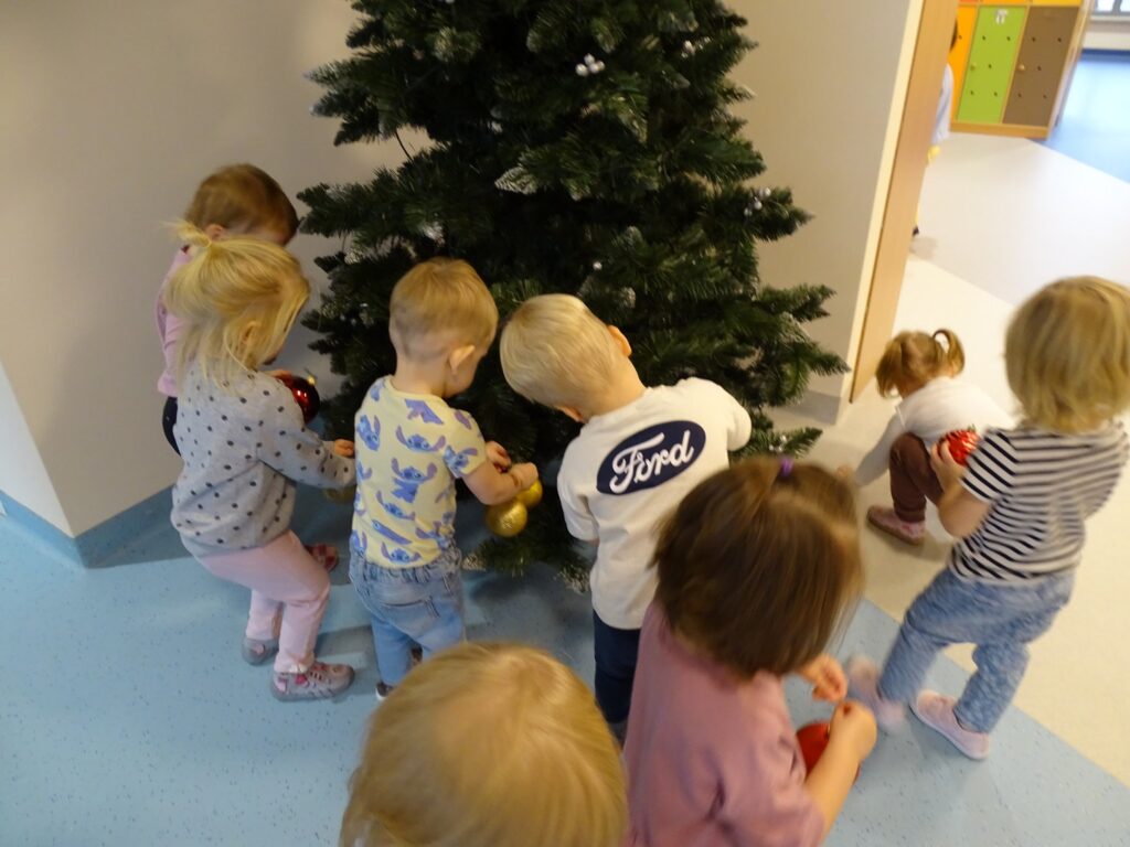 Dzieci zakładają bombki na choinkę