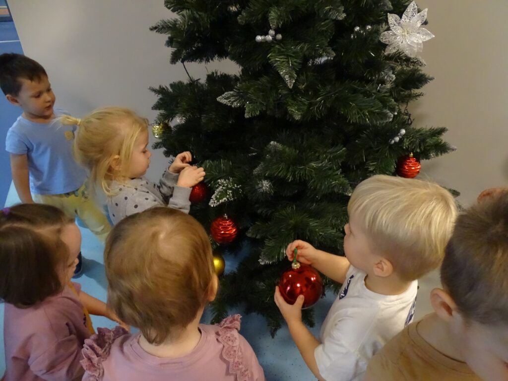 Chłopczyk wiesza czerwoną bombkę