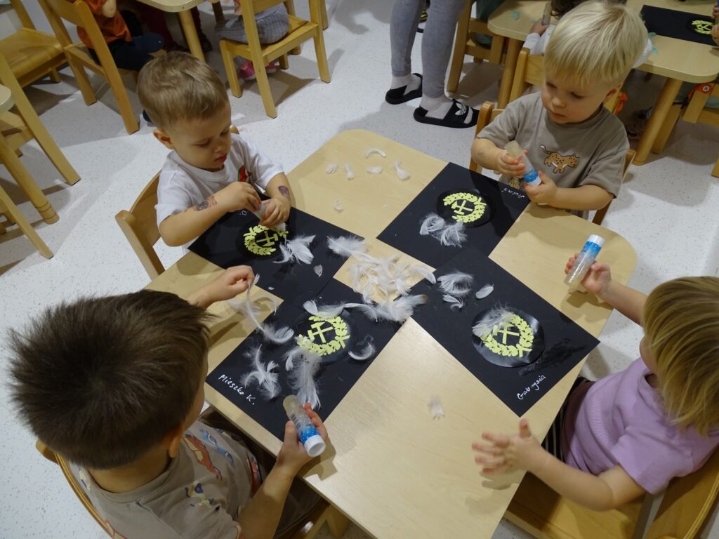 Chłopiec nakleja białe pióra