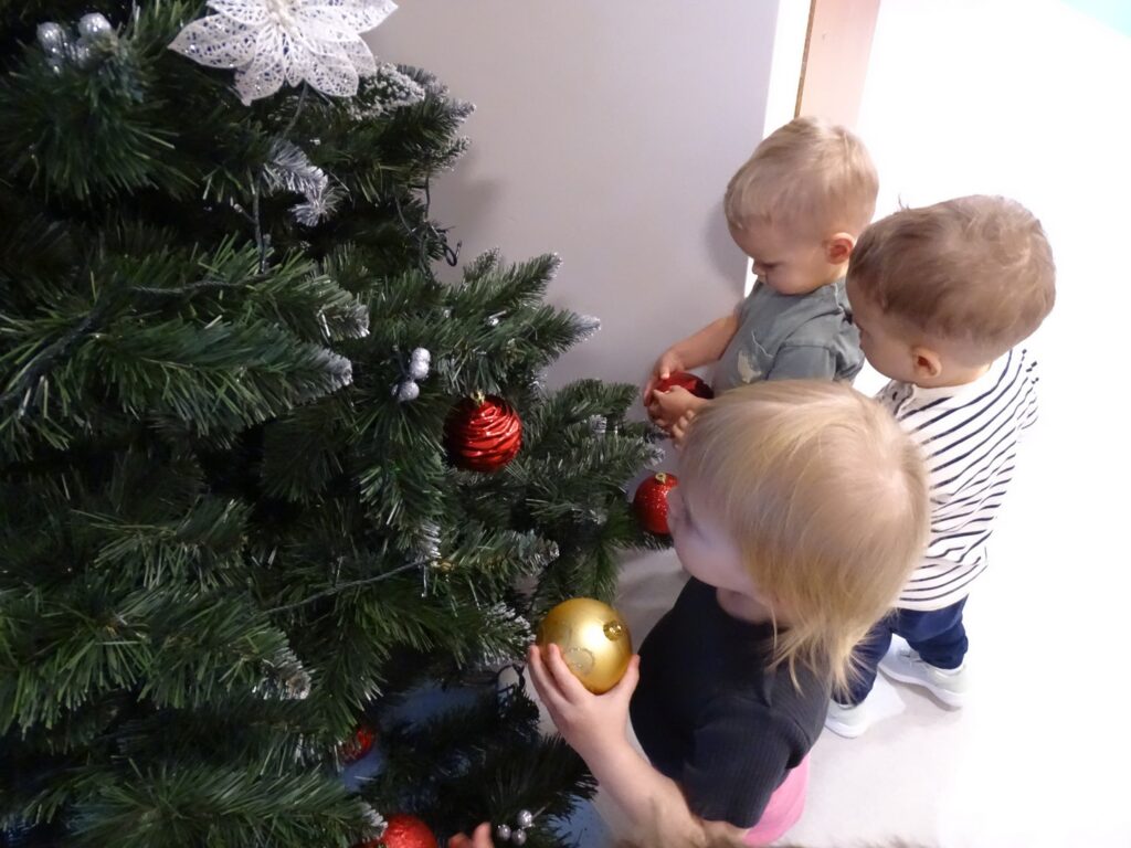 Dziewczynka wiesza złotą bombkę na choince