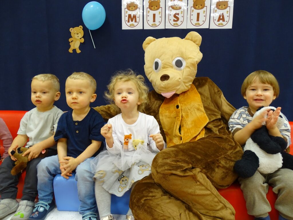 Dzieci siedzą z misiem na kanapach