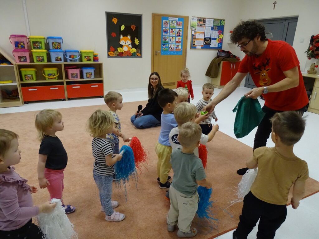 Pan Jacek rozdaje dzieciom grzechotki i pompony