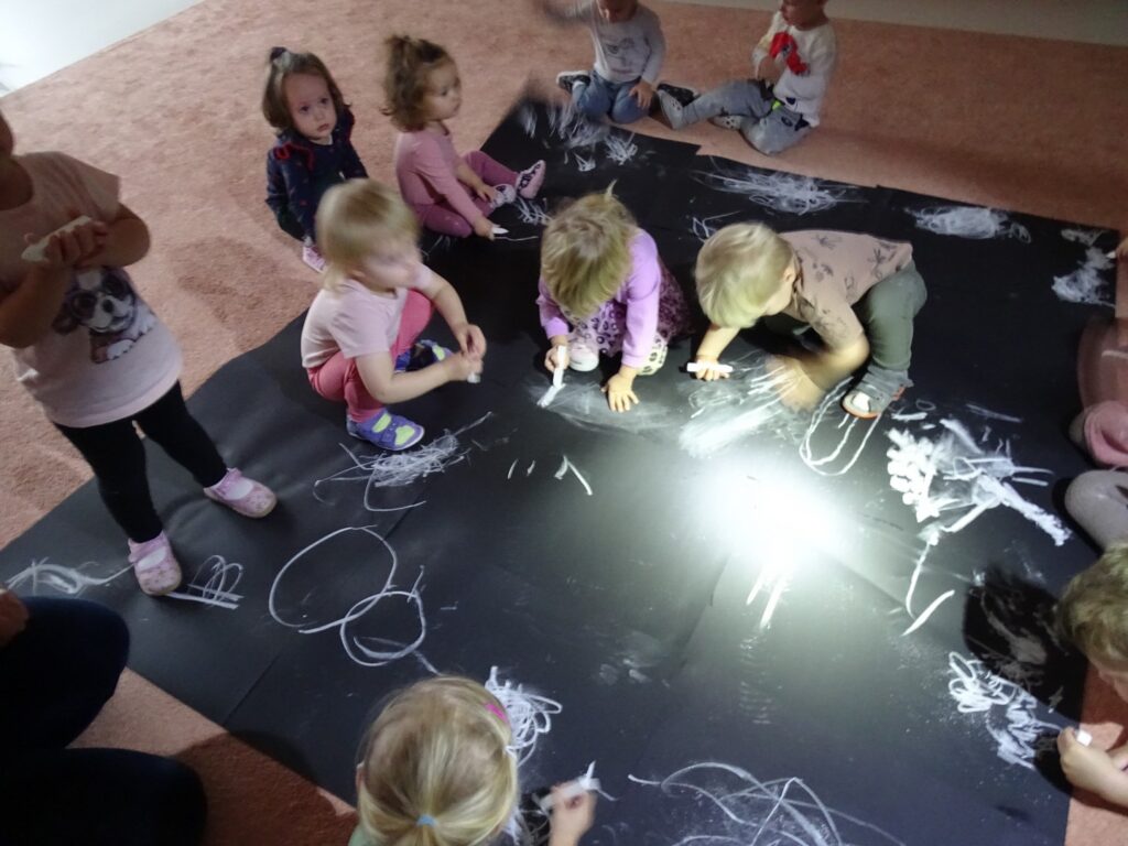 Dzieci malują kredą po czarnych kartonach
