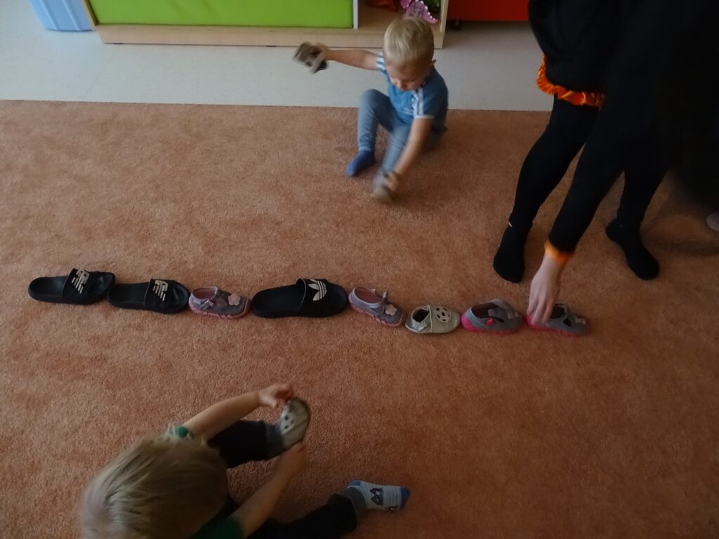 Opiekunka pomaga dzieciom ustawiać buciki