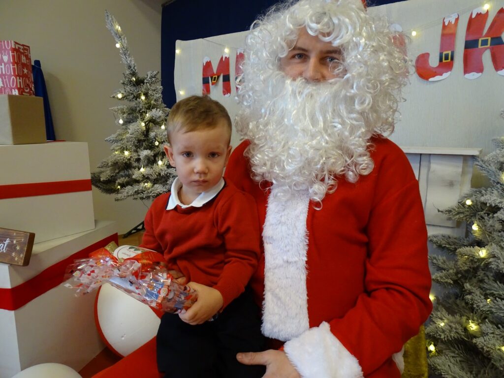 Chłopczyk siedzi na kolanach Mikołaja