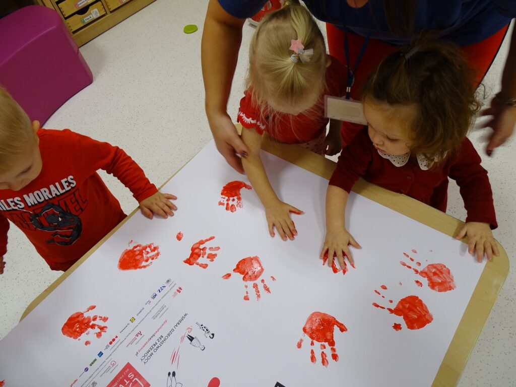 Dziewczynki odbijają rączkę na plakacie