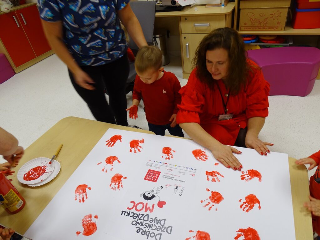 Pani dyrektor wraz z dziećmi wykonuje plakat