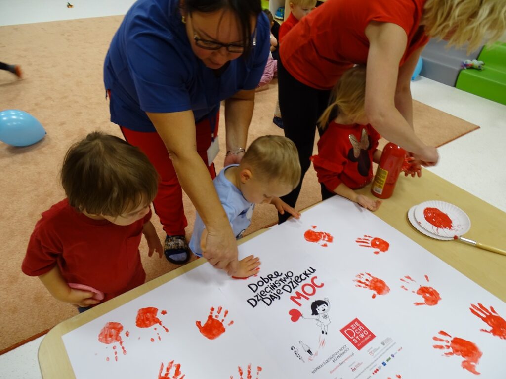 Chłopczyk odbija rączkę pomalowaną na czerwono