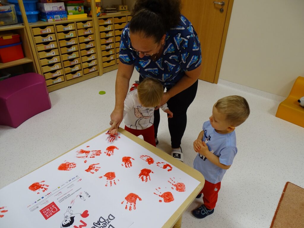 Dzieci odbijają rączki na wspólnym plakacie
