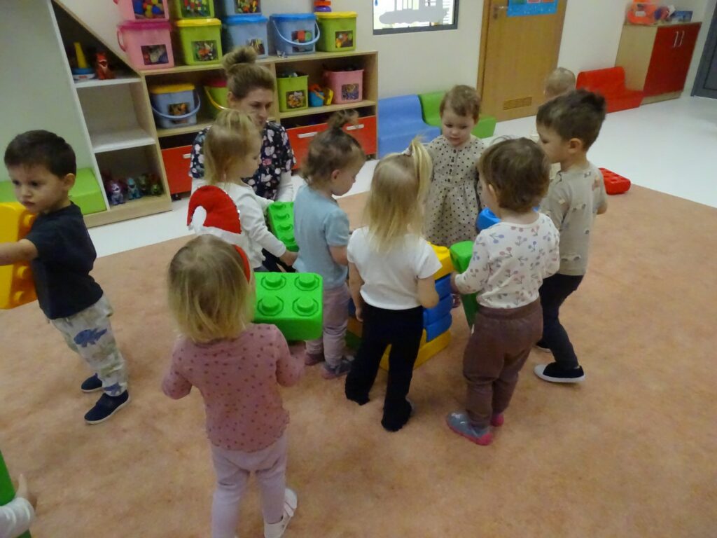 Dzieci próbują tworzyć choinkę z kolorowych klocków